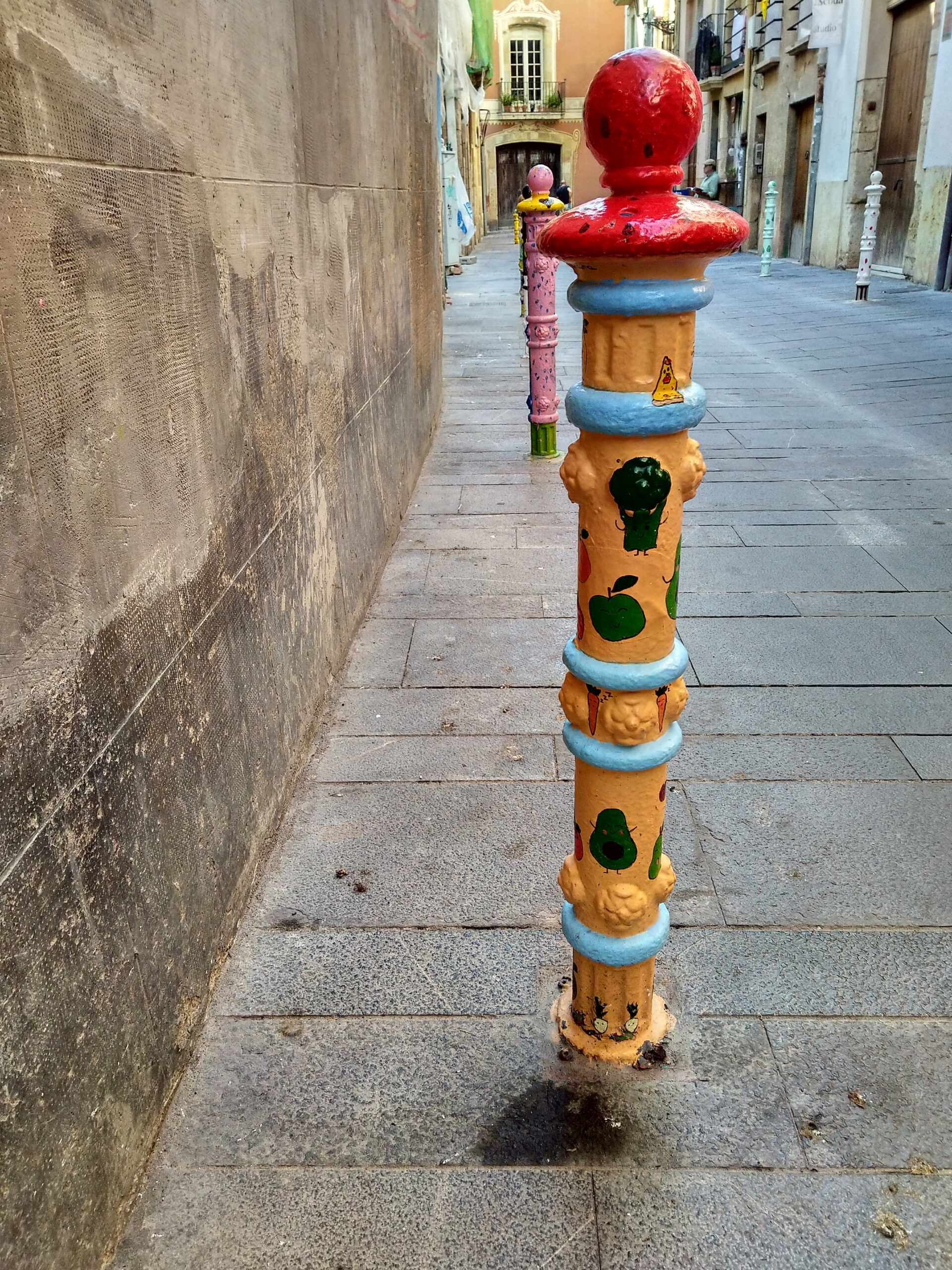 Kolorowe słupki na ulicy del Comte w Tarragonie jako przykład street artu